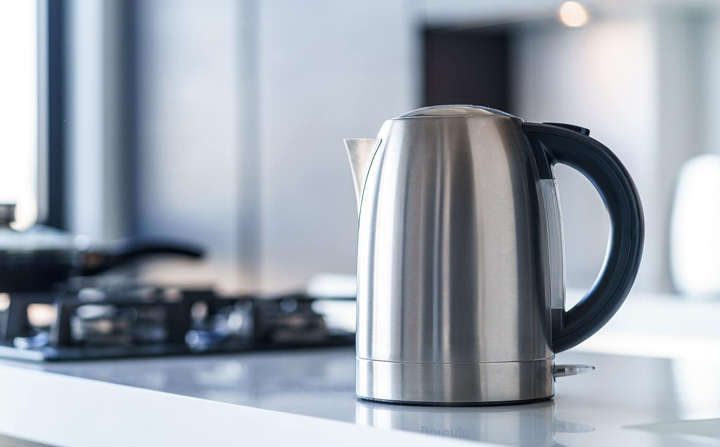Silver metal electric kettle for boiling water and making tea on a table in the kitchen interior. Household kitchen appliances for makes hot drinks