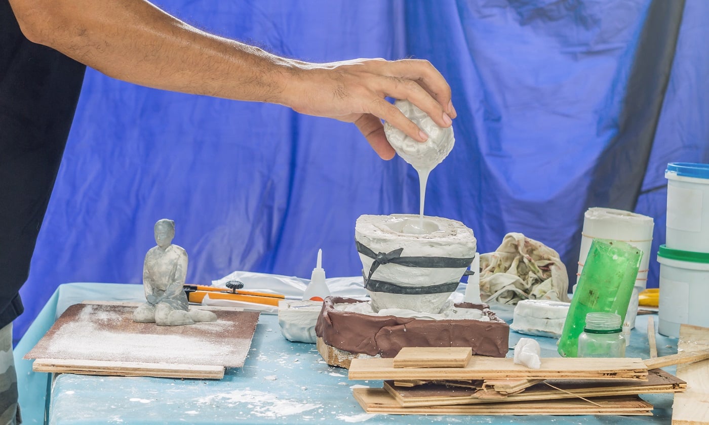 Artist pouring liquid resin in a mold to make a female figure