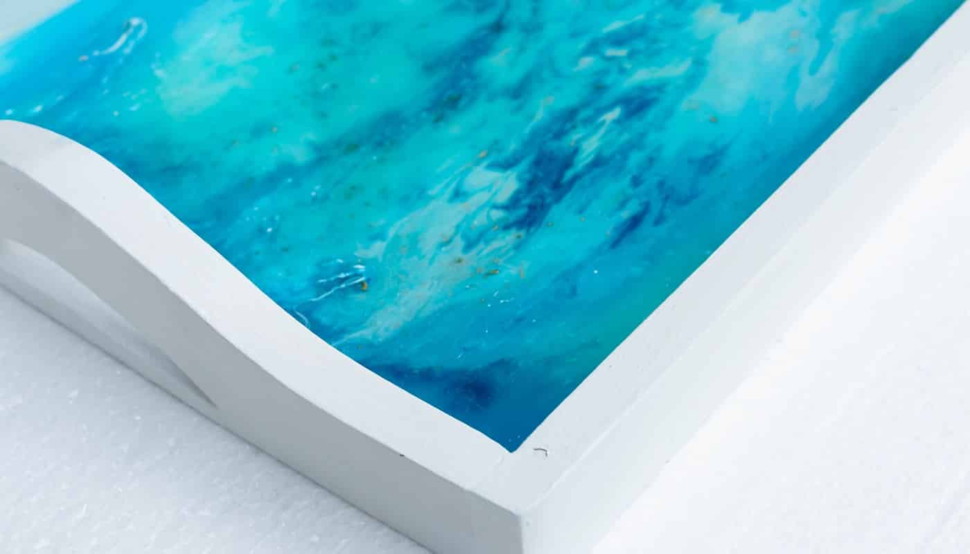 A closeup shot of a white tray with epoxy resin art with blue alcohol inks