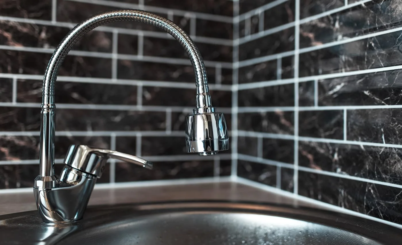 Picture of silver faucet in kitchen area, on the background of dark brick wall. Kohler K-596-VS Review