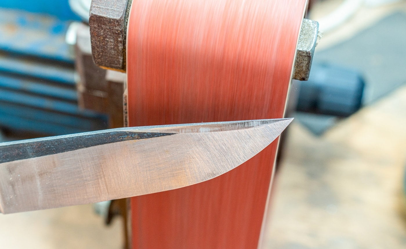 Grinding polishing sharpening knife blade on the belt grinder sander equipment. Knife making.