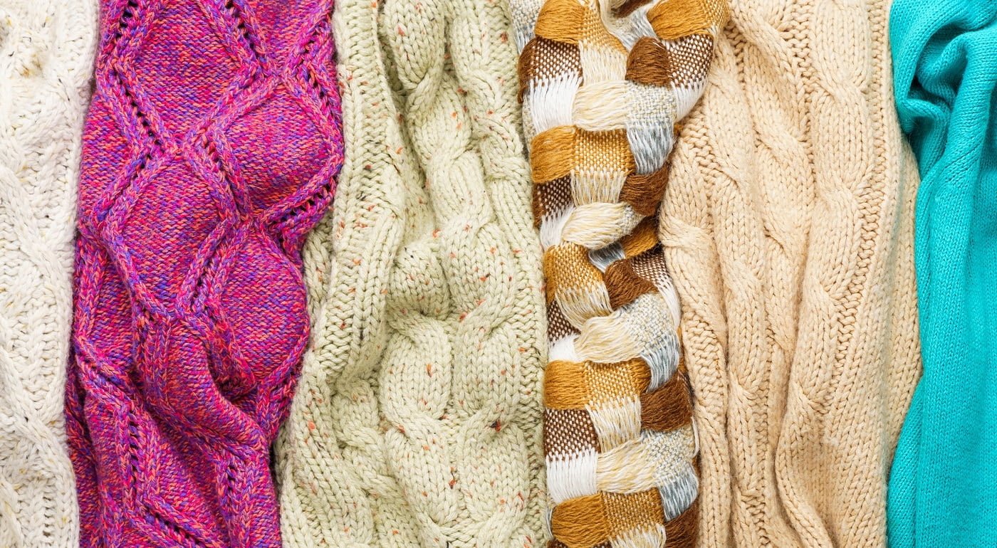 Several Different Colorful Knitted Sweaters Lays Side by Side as Background
