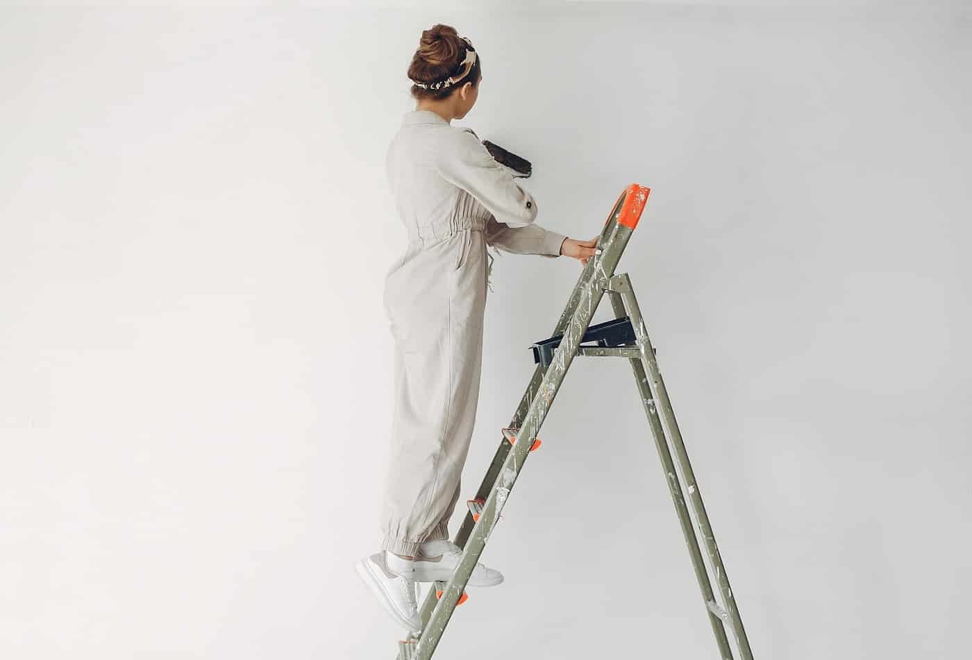 Woman repairs. Girl at home. Woman in a white overalls.