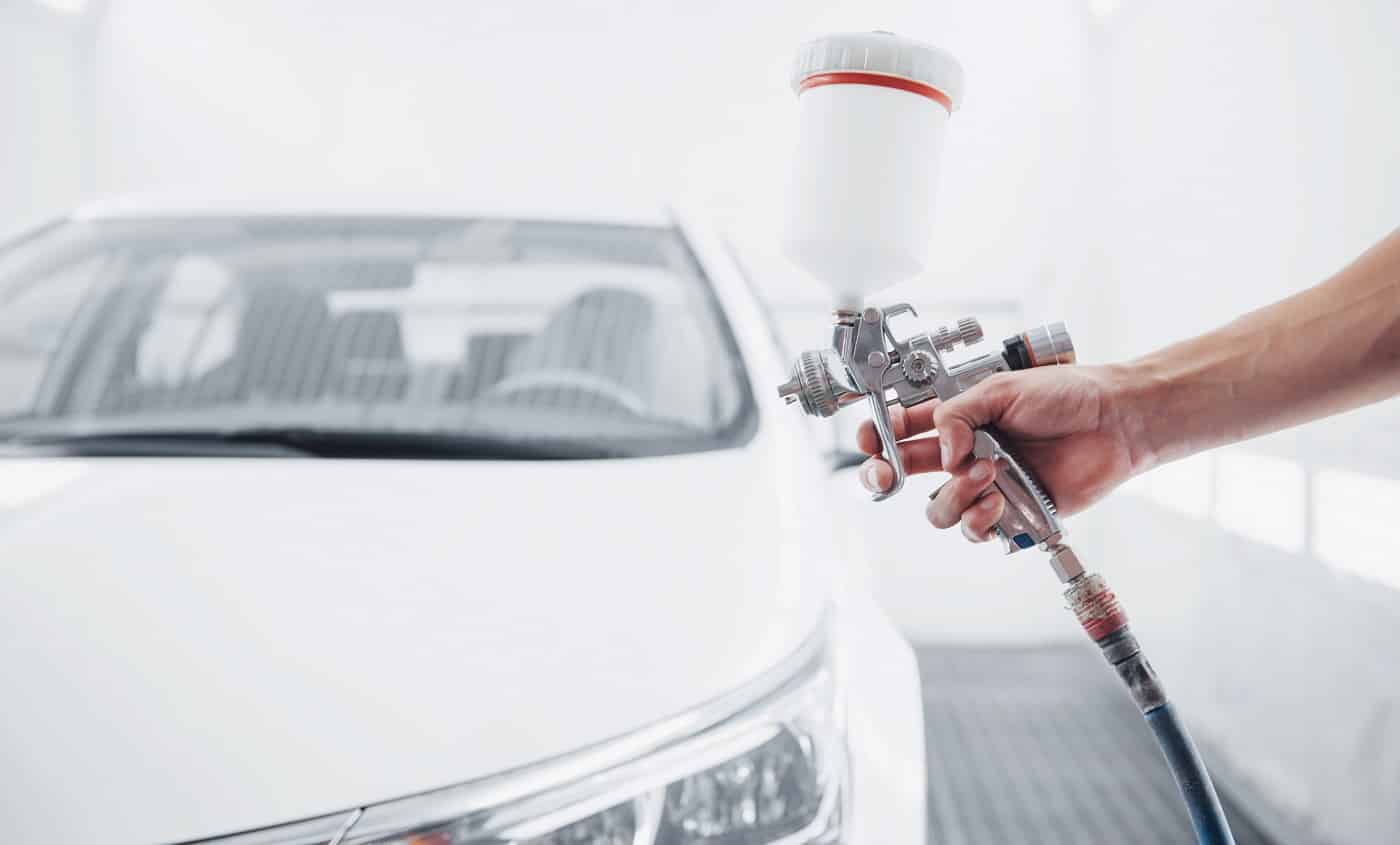 gun with paint in the hands of a man to paint a car.