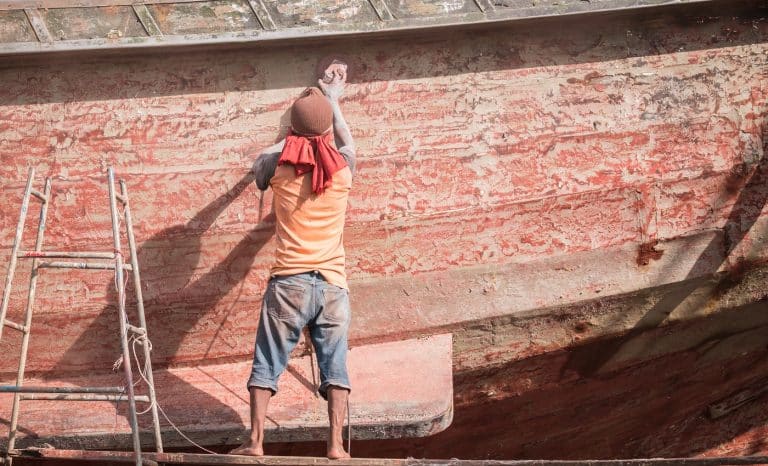 Boat Hull repairs/ A man using grinder in preparation for anti foul paint being applied