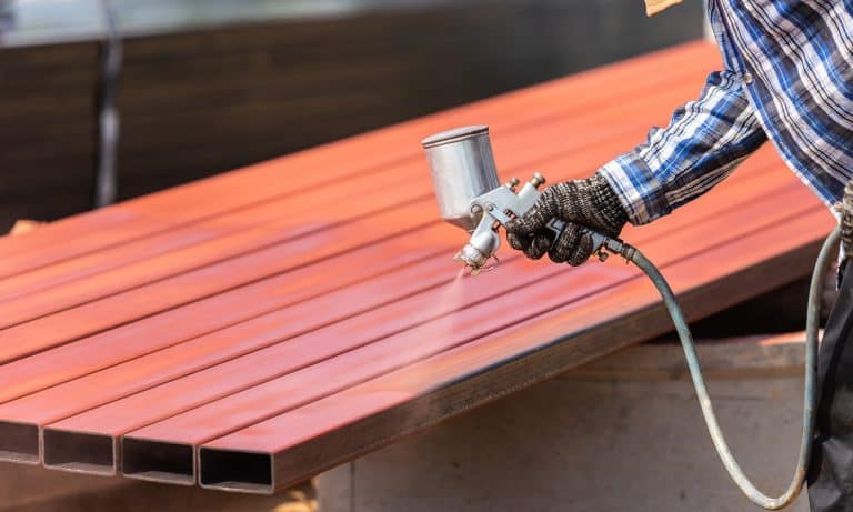 Construction worker spraying paint to steel pipe to prevent the rust on the surface