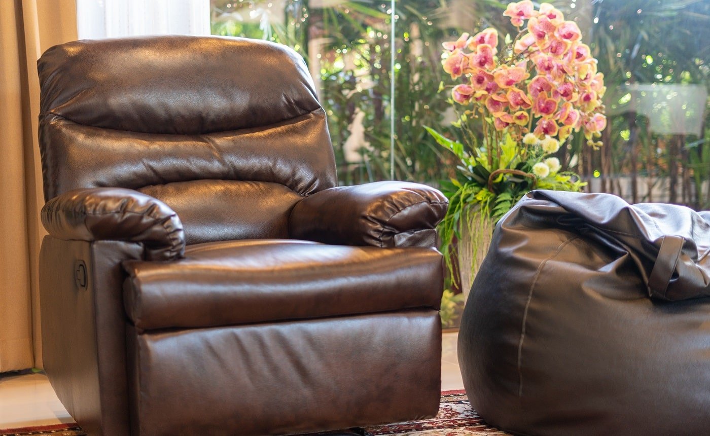 Interior design of house, home, villa feature leather couch,bean bag, artificial flower and a view of garden from living room