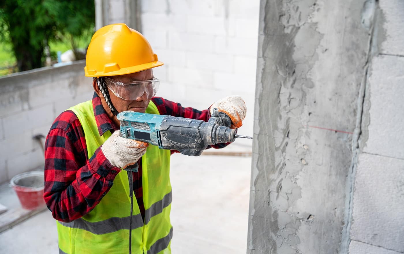 tiler using electric impact drill to drilling cement wall at unfinished house construction