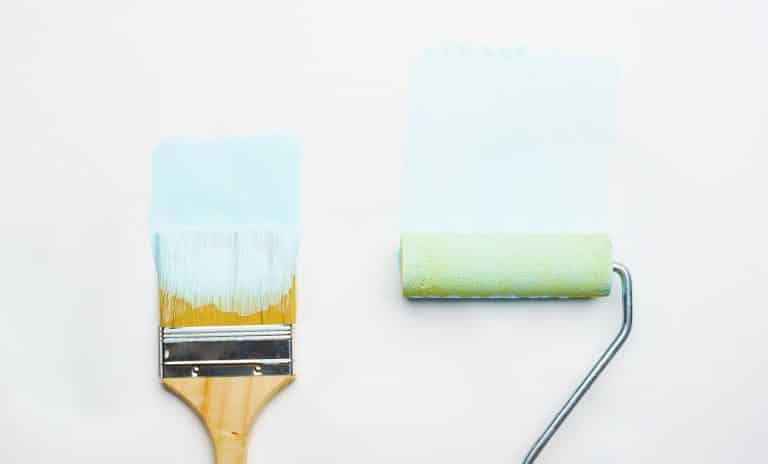 Photo of brush and roller with blue paint on blank white background