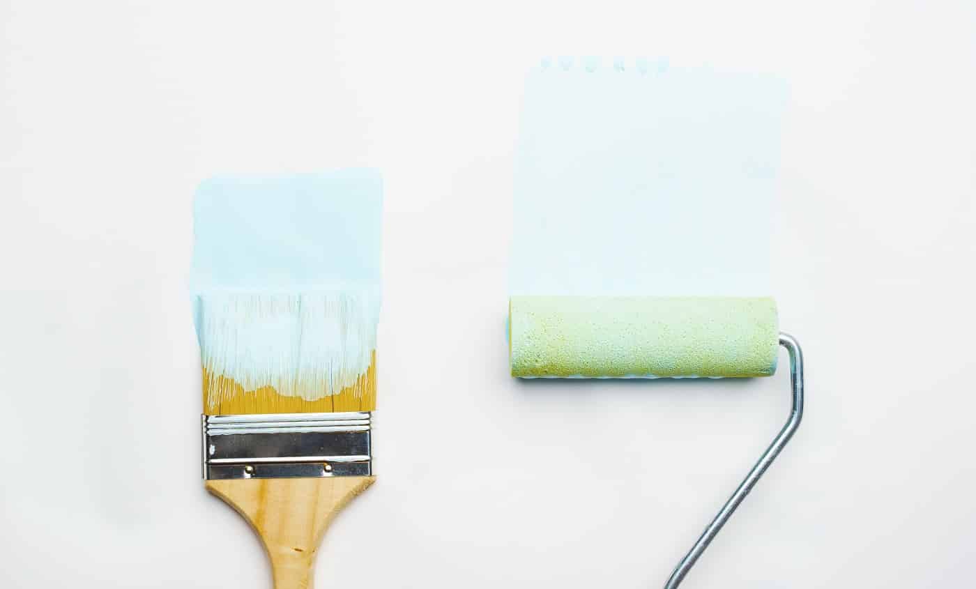 Photo of brush and roller with blue paint on blank white background. Best One Coat Paint and Primer