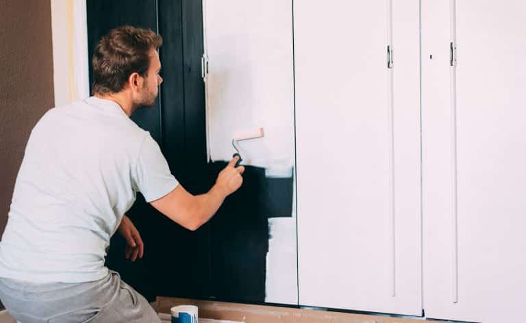 Man painting a wardrobe with a roller