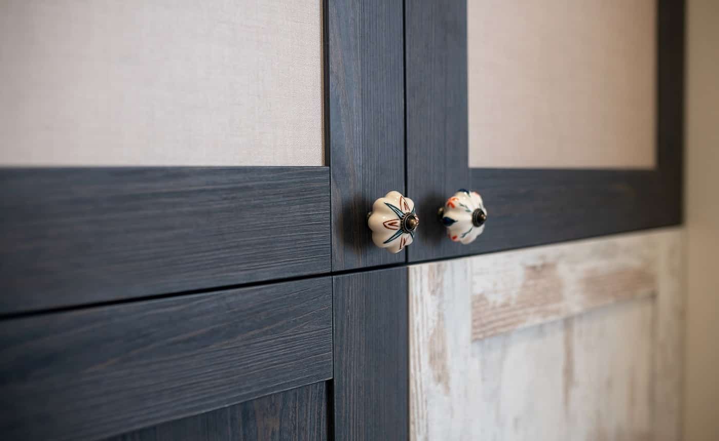 Decorated door handle. Decorative carved handles on matte black and white doors of designer cabinet