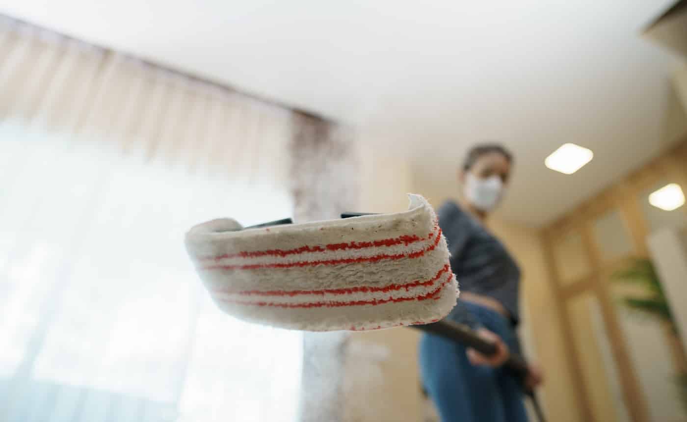 Woman washes the floor with a steam mop.