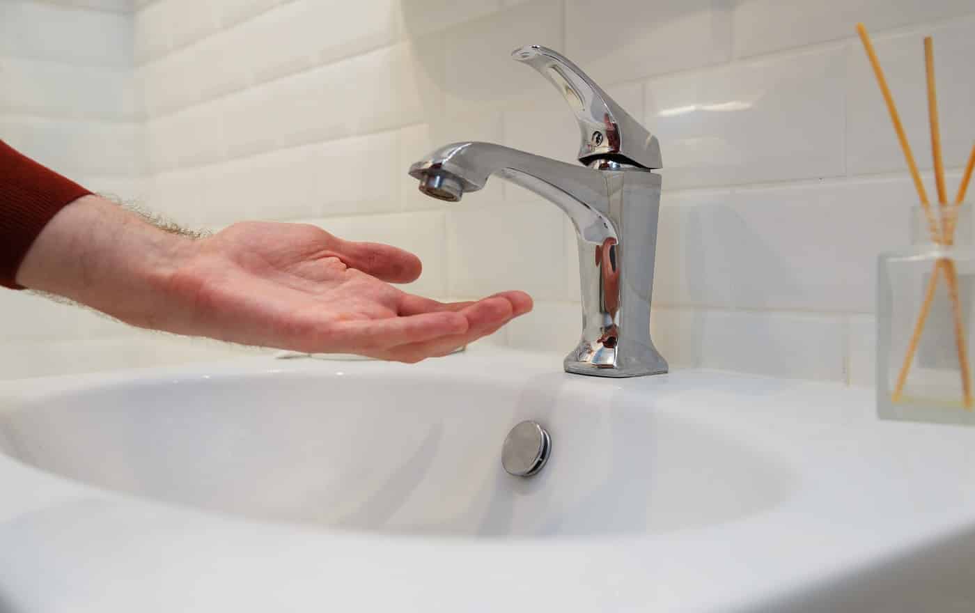 Man holding his hand under opened tap without water. Shutdown of water supply for non-payment or during repair work of the central system