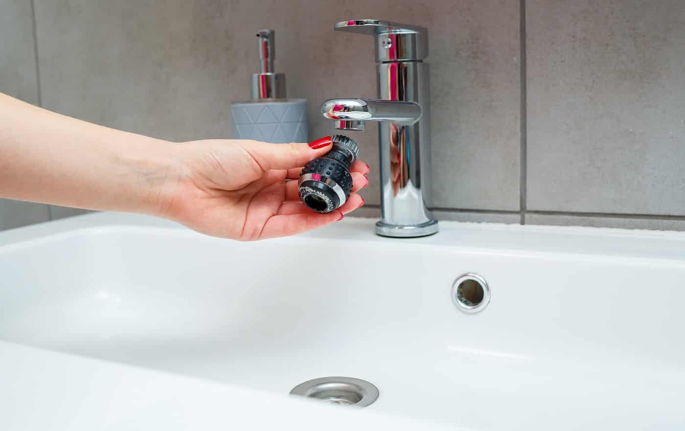 Rotary nozzle on the mixer to adjust the flow of water. White bathroom sink for washing hands