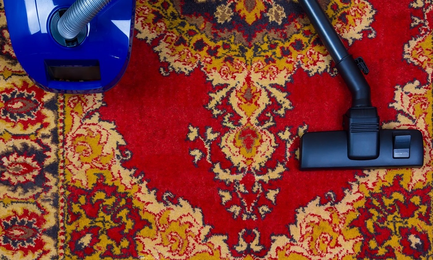 electric vacuum cleaner on the background of an old carpet, top view of flat lay