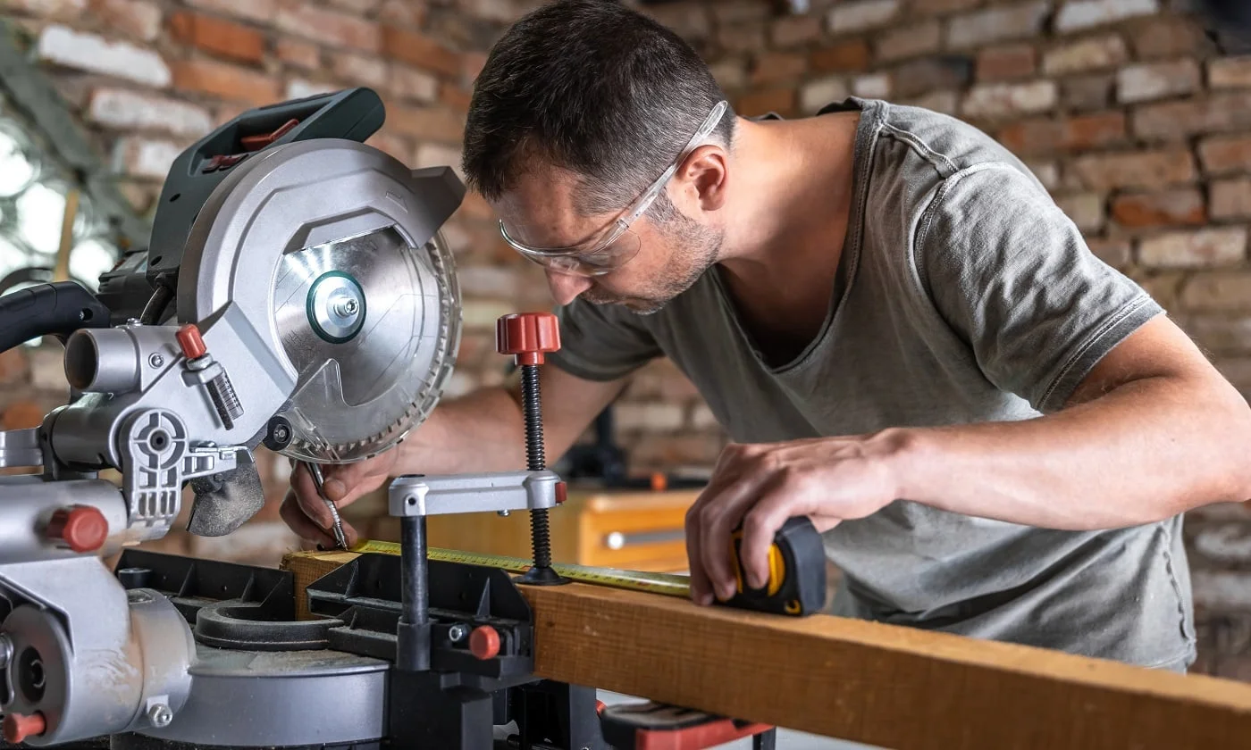 A professional carpenter works with a circular saw miter saw in a workshop.