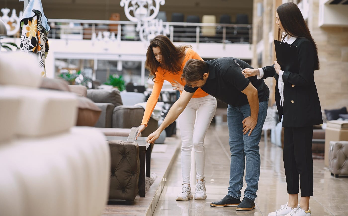 Couple in furniture store. Family choosing furniture in store while sales clerk consulting them.