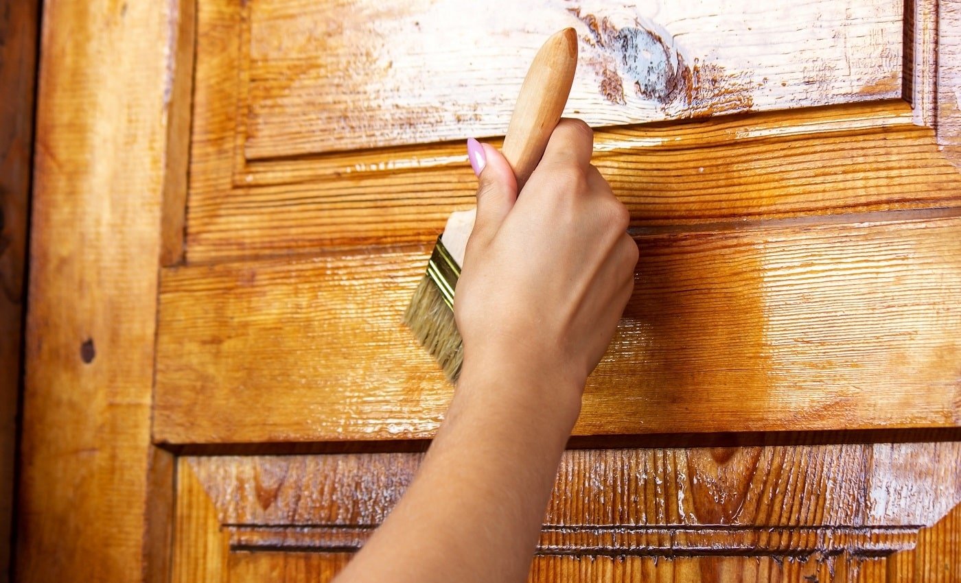 Beautiful young girl paints a wooden door. Summer work in the garden. Selective focus