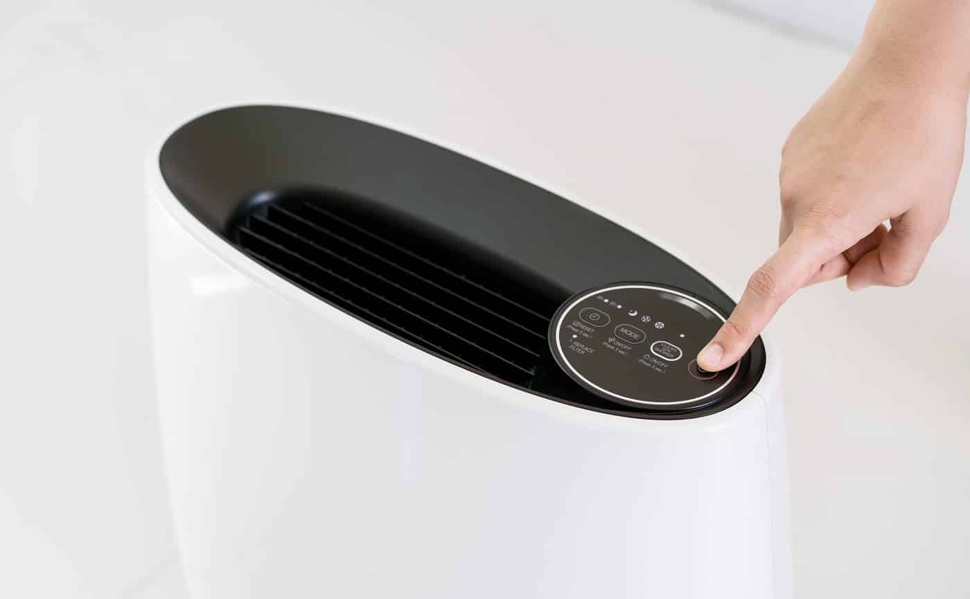 Asian woman relaxing in the living room while the modern portable air purifier working. Woman using air purifier in the living room to purify or clean the polluted air and atmosphere.