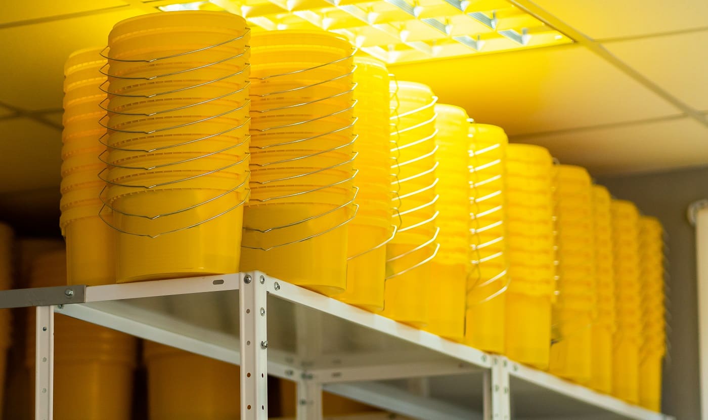 Many yellow color buckets cans in row with ink paint row