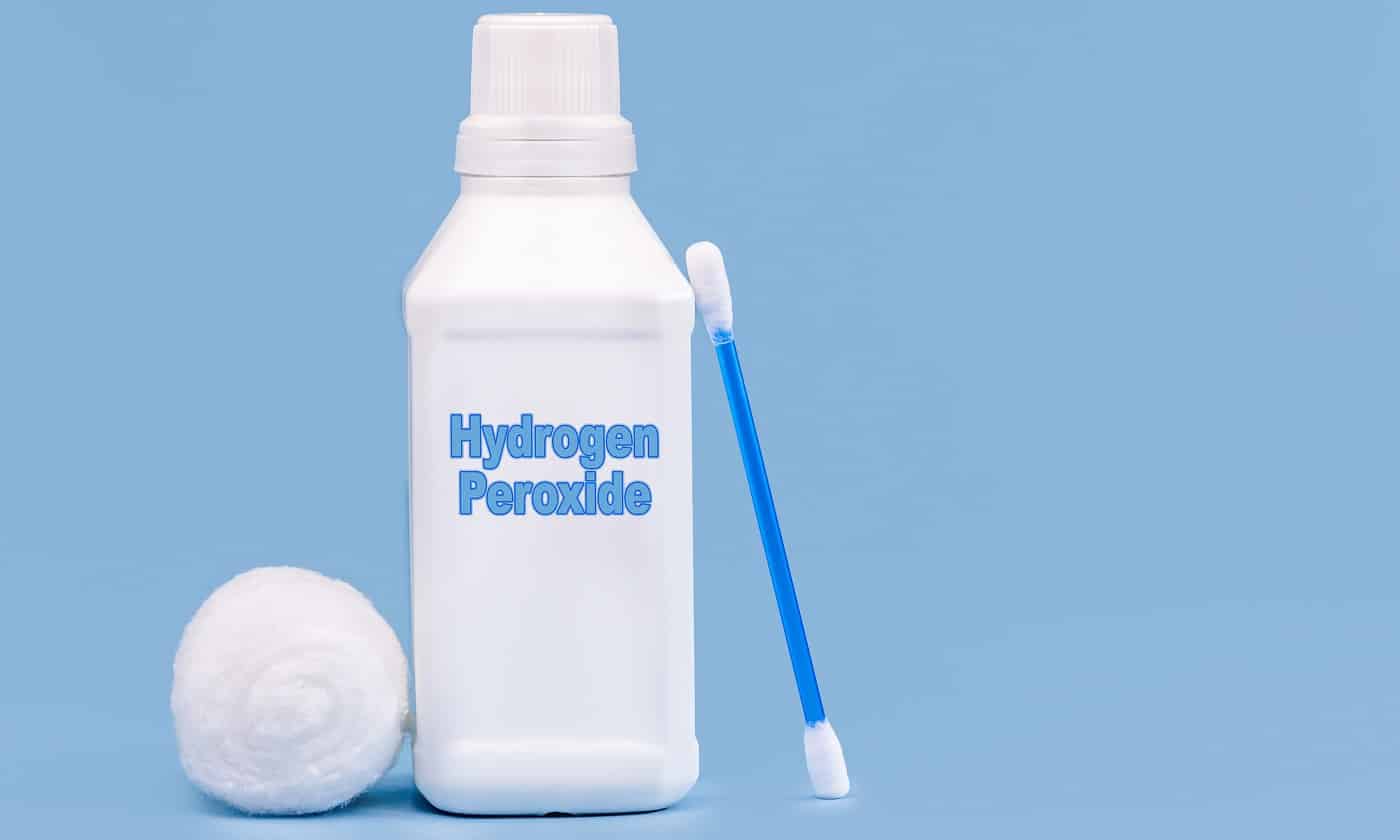 plastic container, medicine bottle, written in English: hydrogen peroxide, isolated blue background, concept of first care