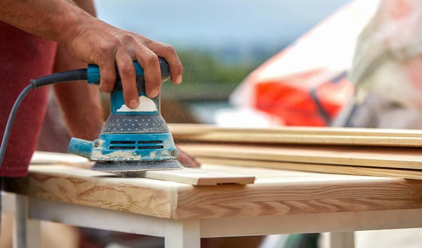 Grinder worker polishes a wooden board. Sanding boards Orbital eccentric machine