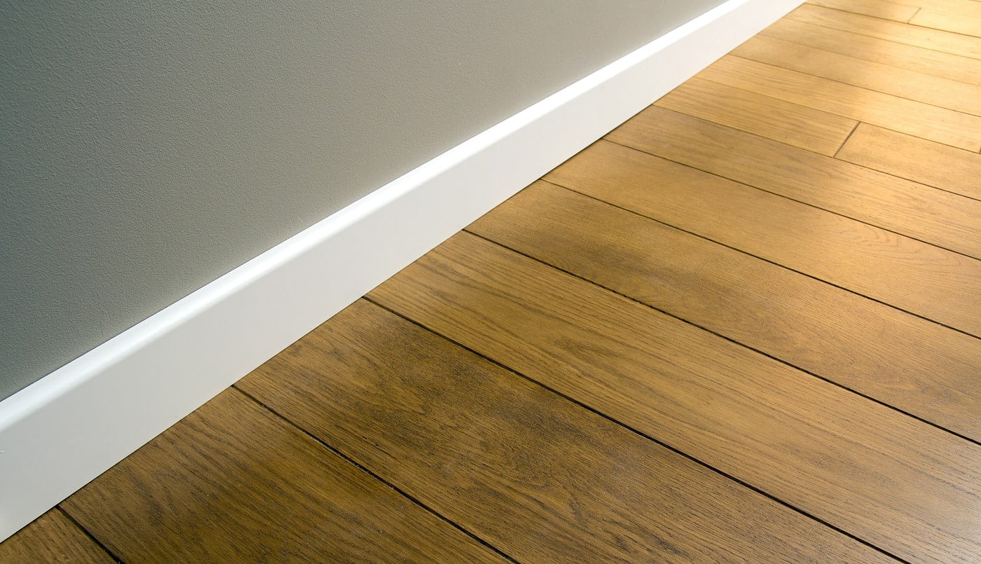 Close up of white plastic plinths on dark wooden oak floor parquet.