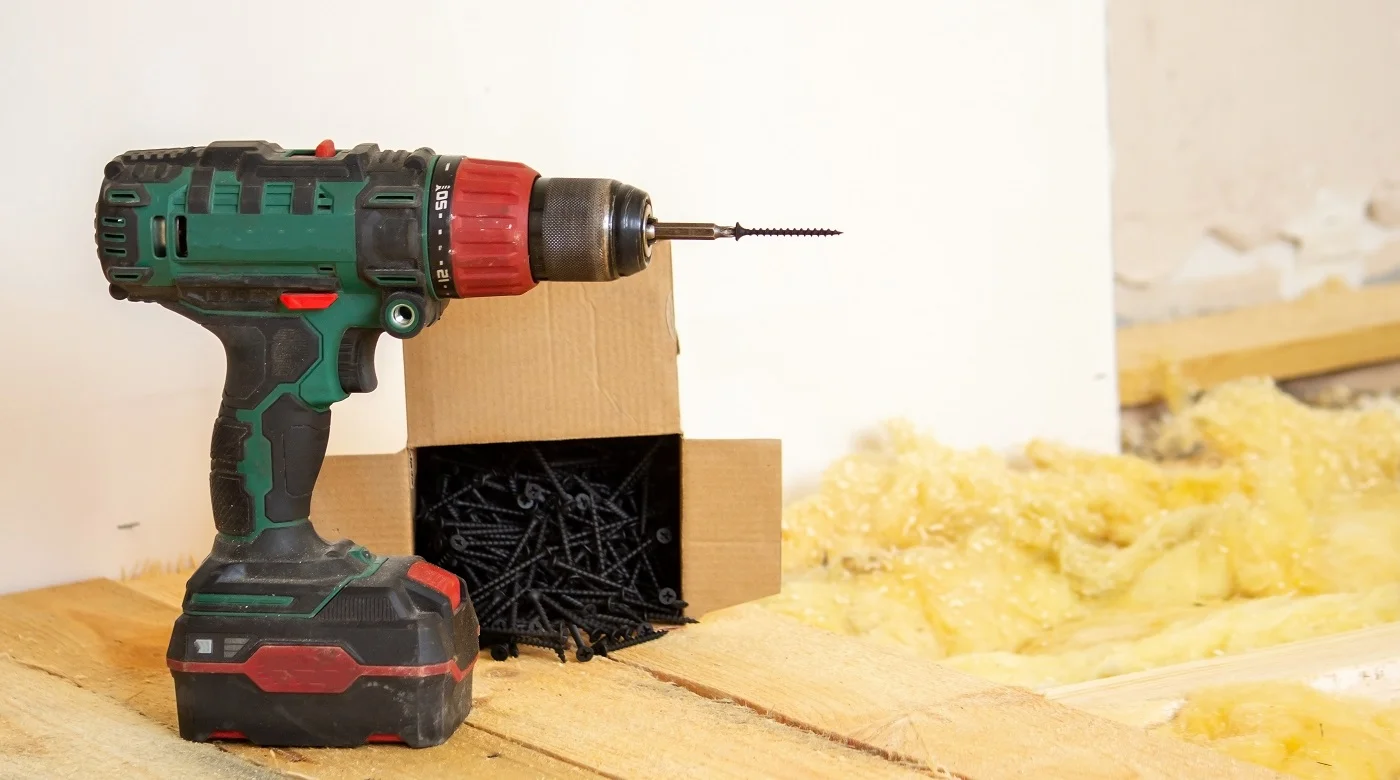 A man makes repairs in the house, a screwdriver, screws, a saw. Wooden floor. Selective focus