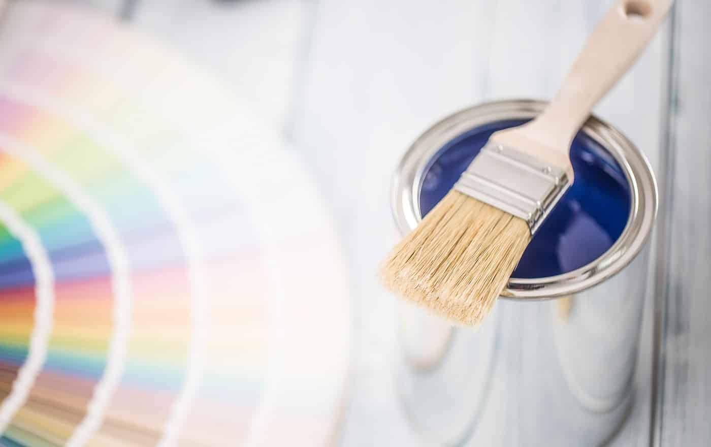 Paint cans brush and color palette on table Sherwin Williams vs. Benjamin Moore