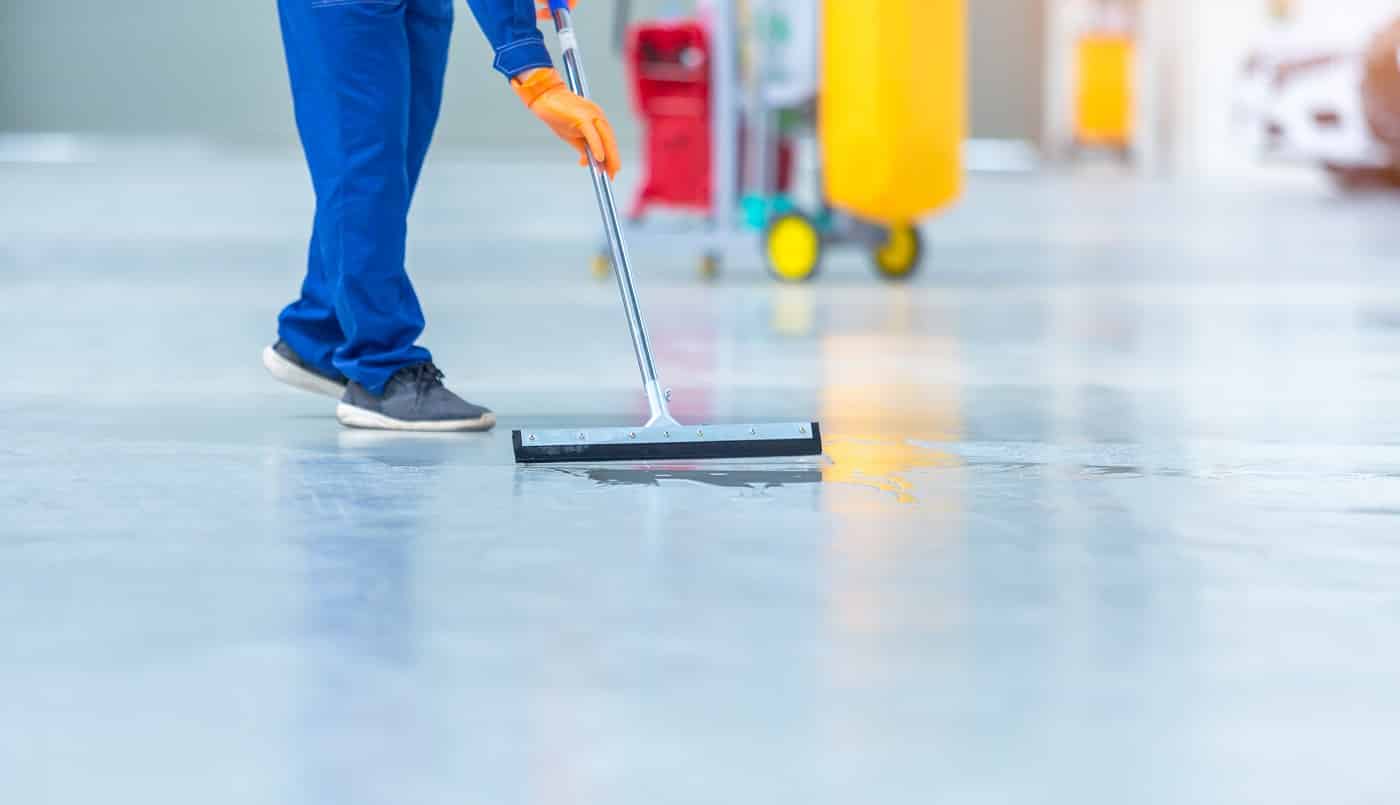 Car mechanic repair service center cleaning using mops to roll water from the epoxy floor. In the car repair service center.