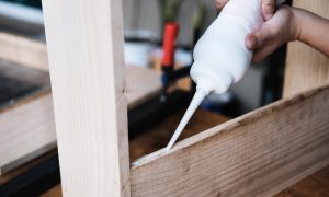 Woodworking operators are using glue to put together the wood parts to assemble and build a wooden table for their customers