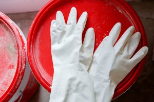 White used latex gloves lie on a bucket of the Best glue for rubber