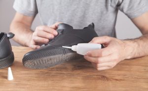 Man fixing shoe with the best glue.