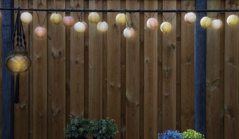 Glowing lanterns lampion lights with delicate design hanging wooden fence,decorative stylish design with copy space. cozy garden decoration space for text