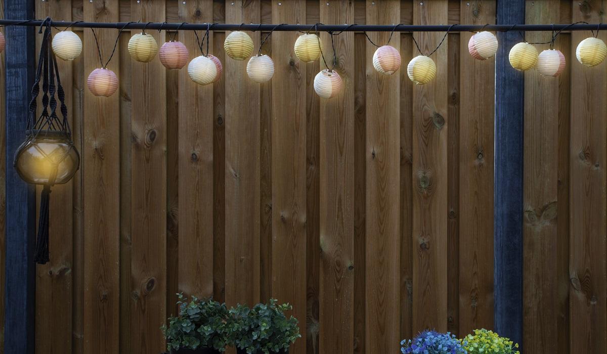 Glowing lanterns lampion lights with delicate design hanging wooden fence,decorative stylish design with copy space. cozy garden decoration space for text