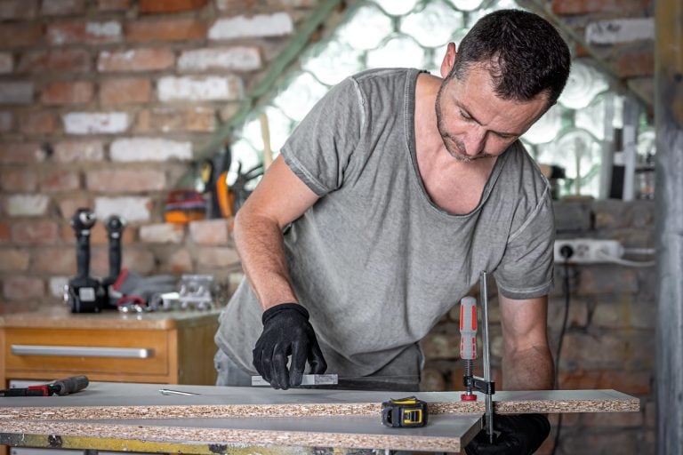 Carpenter doing wood work using clamping hand tool in his workshop.