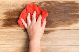 A man's hand Using red rags wipe the wooden floor.