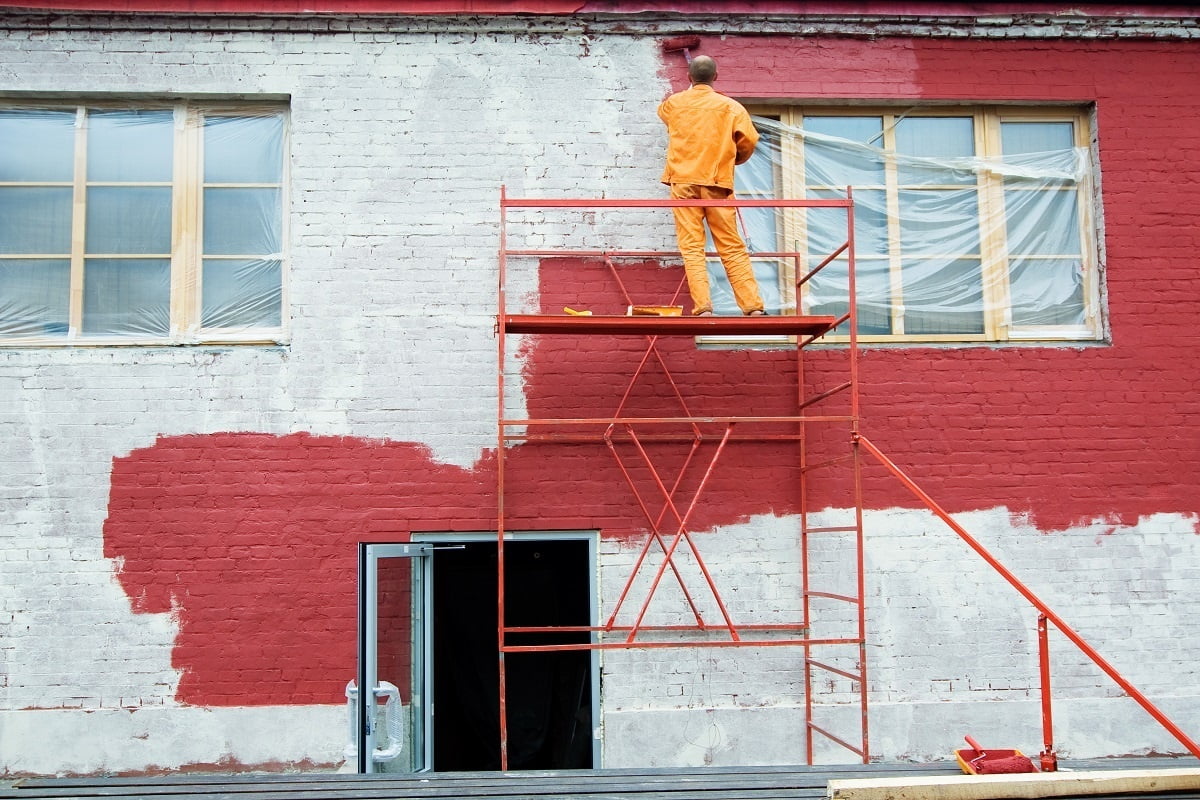 Man painting a brick wall in red