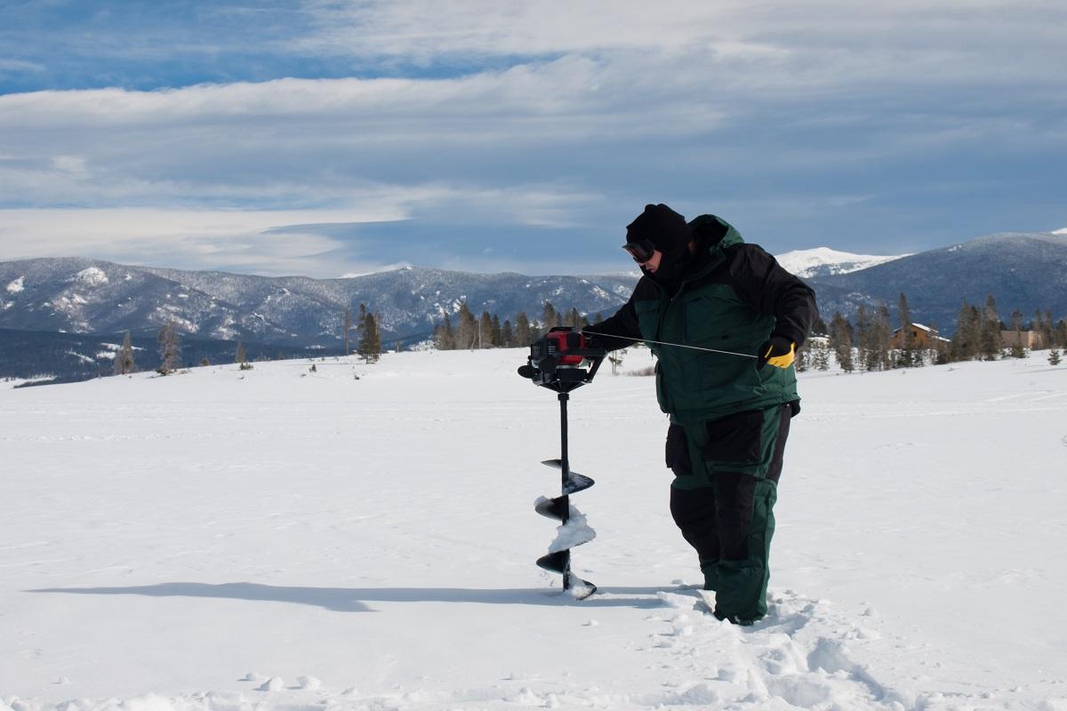 Fisherman with an auger bit on the frozen lake Granby, Colorado.