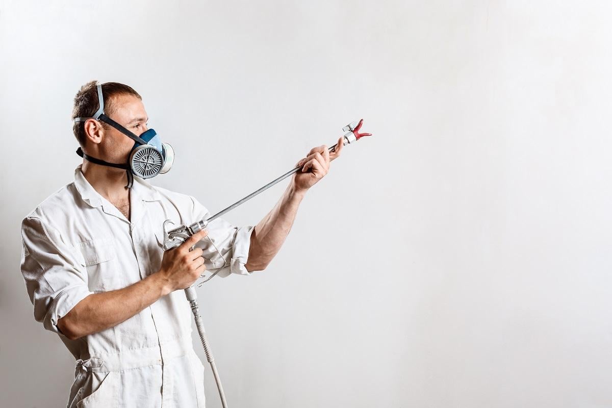 Worker painting wall with spray gun in white color. Copy space. Best Black Mold Remover Spray