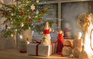 Christmas lantern, Christmas gnome, Christmas tree and red décor on the window of a wooden house overlooking the winter garden. Best Christmas Window Decorations