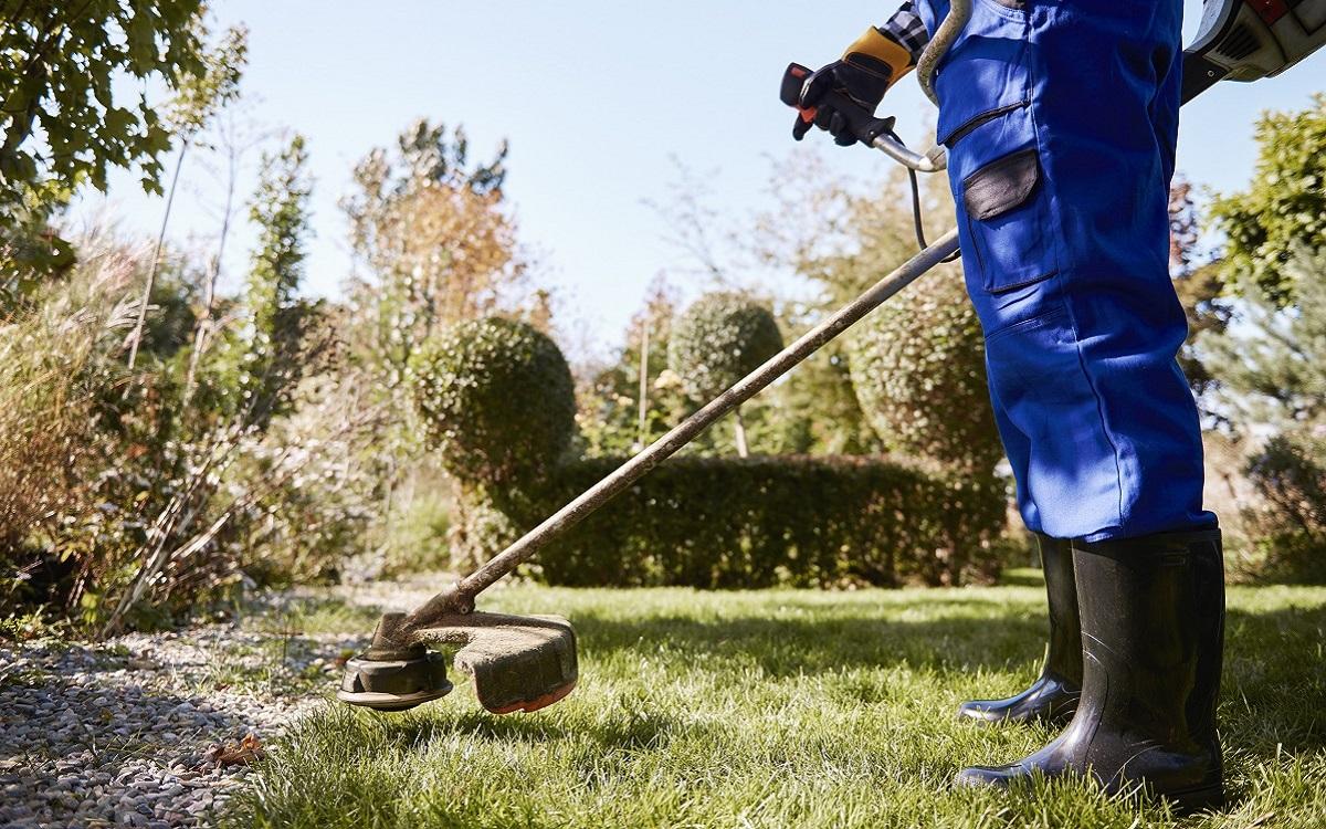 Gardener with weedwacker cutting the grass in the garden. Best Corded Electric String Trimmer