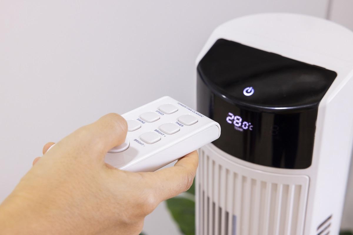 Close-up Asian woman hand, pressing a button remote control to air purifier machine in a bedroom. Protect PM 2.5 dust and air pollution concept. air cleaner removing fine dust in house.