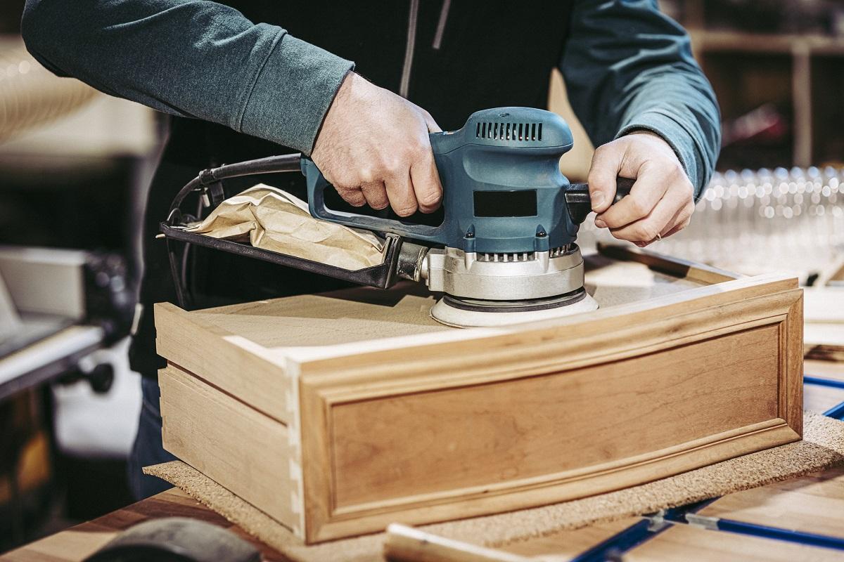 detail of a carpenter using an orbital sander. Orbital Sander With Vacuum Attachment Buying Guide