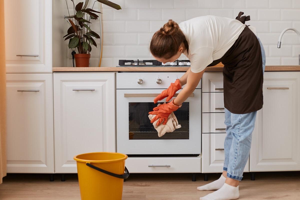 Indoor shot of woman washing steel gas stove and oven with Oven Cleaners Buying Guide