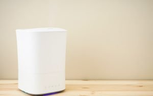 Modern air humidifier on a wooden table. Place for text.