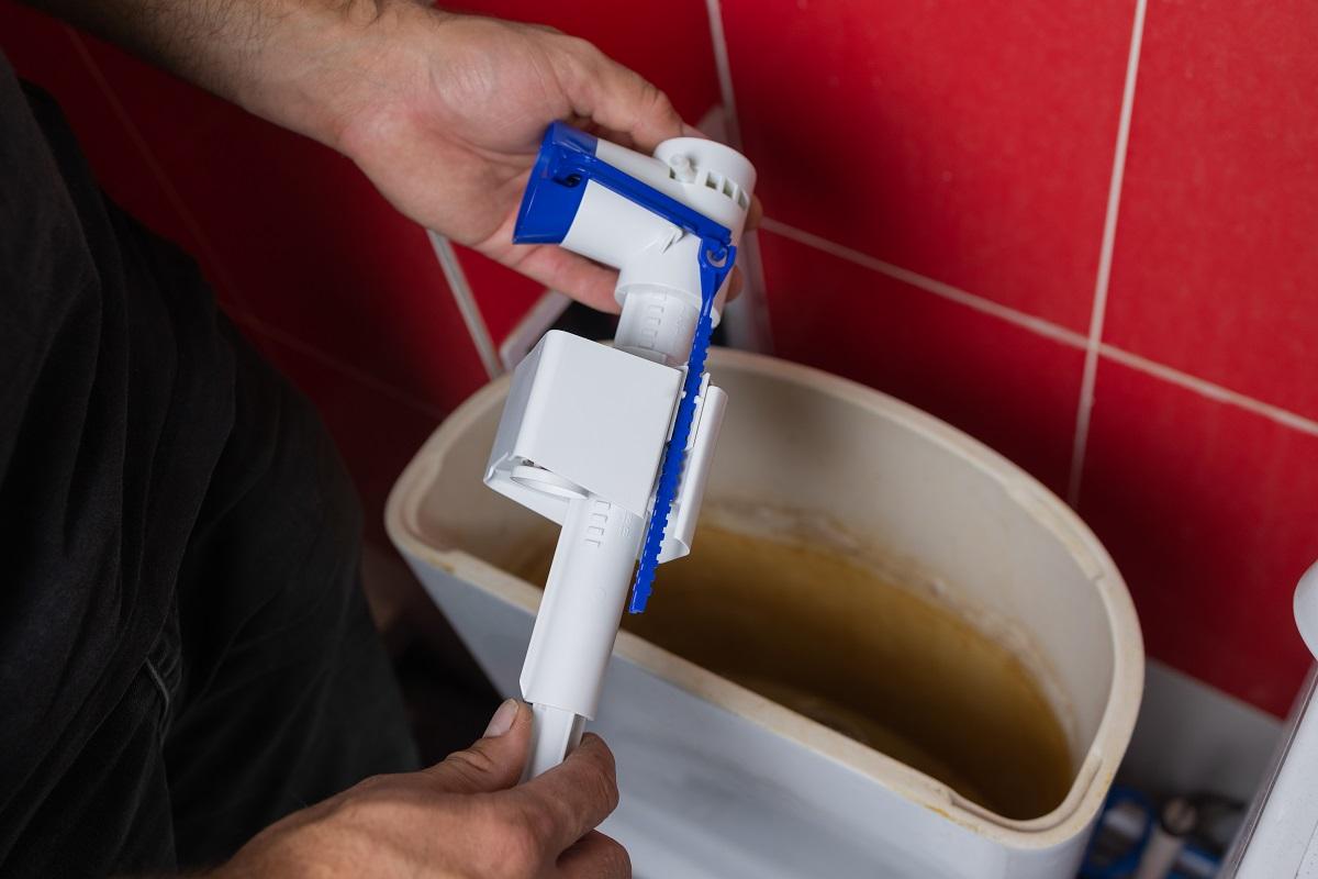 5 Best Epoxy For Toilet Tank Repair | Reviews & Buyer's Guide Toilet tank parts replacement. A man in orange gloves repairs the toilet tank drain