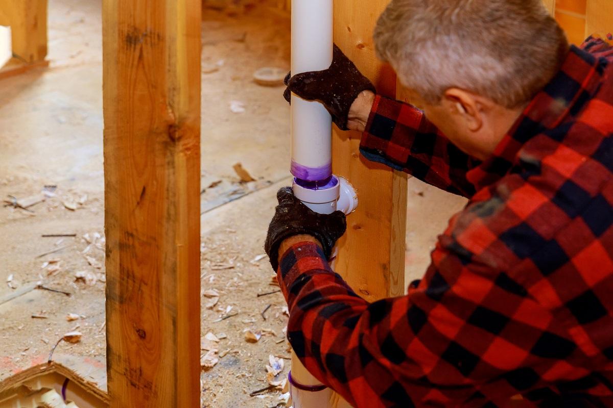 Plumber joining assembly plastic pipes with glue cement for drains under construction