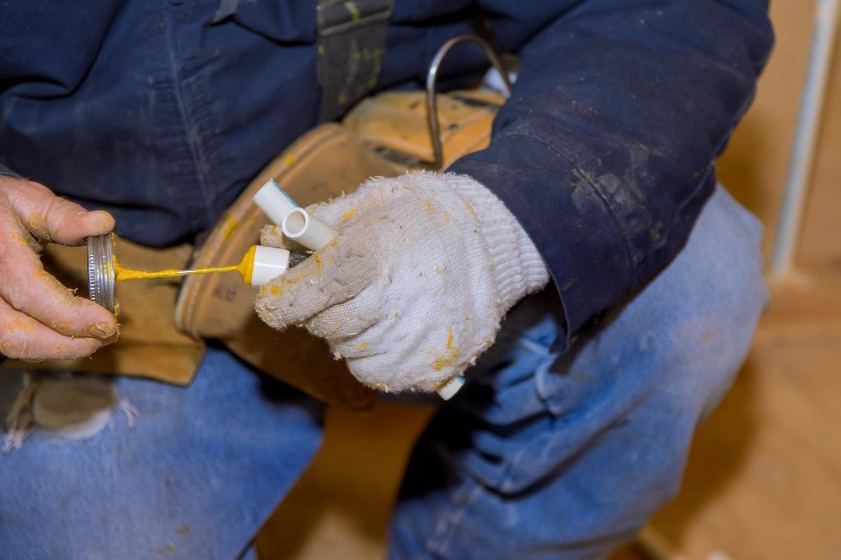 Man gluing parts cement glue off a piece of polypropylene pipes for installation water line of a new home under construction